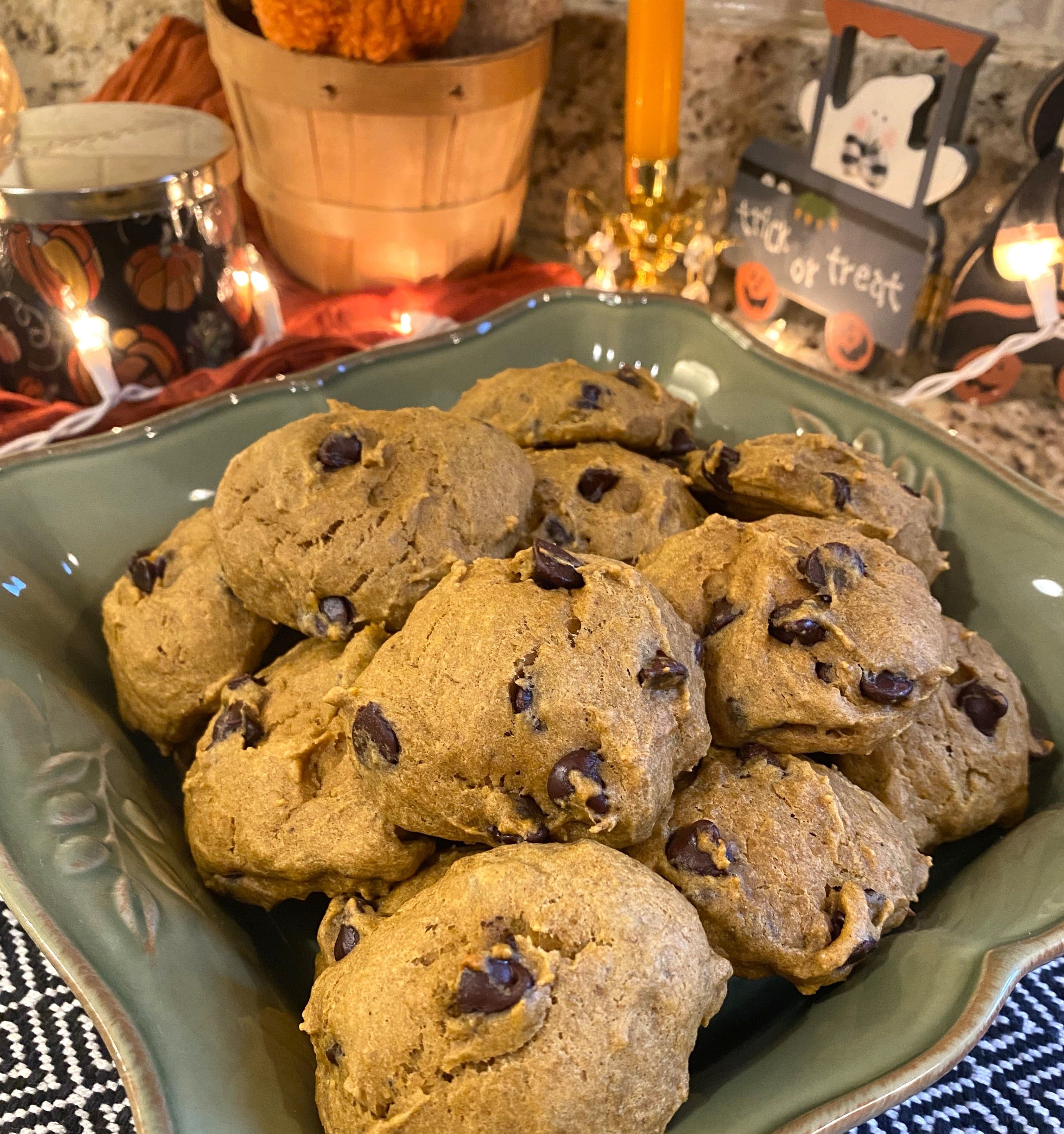 pumpkin banana chocolate chip cookies in a green serving dish with Halloween decorations in the background